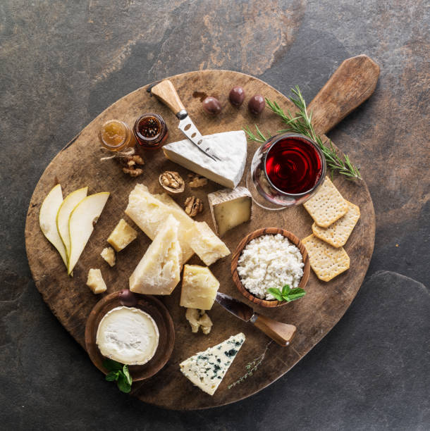Cheese platter with different cheeses, fruits, nuts and wine.