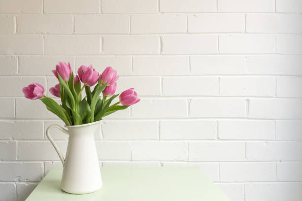 istock Pink tulips on green table in white jug 1129909483