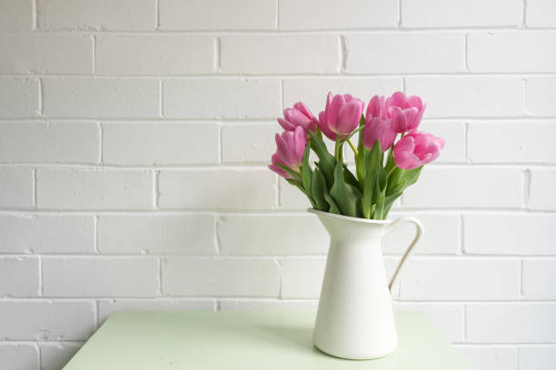 istock Pink tulips in white jug on green table 1129909620
