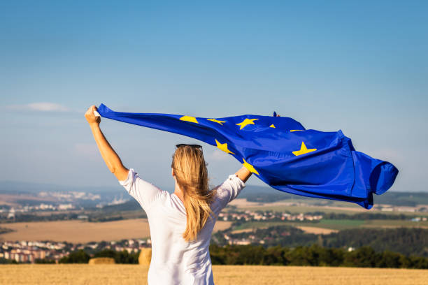 donna che sventola bandiera dell'unione europea all'aperto. - euro symbol caucasian europe european culture foto e immagini stock