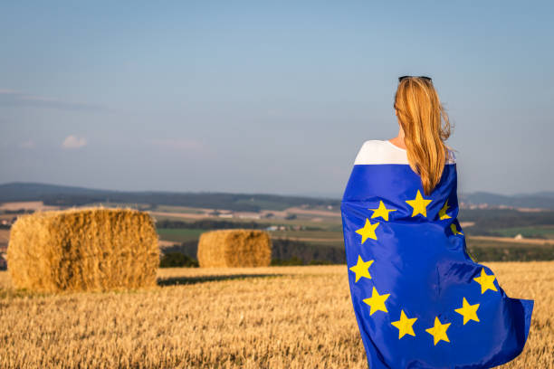 istock Woman in EU flag looking at coutryside. 1129916941