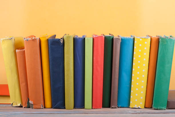 istock Book stacking. Open hardback books on wooden table and yellow background. Back to school. Copy space for ad text 1129917315