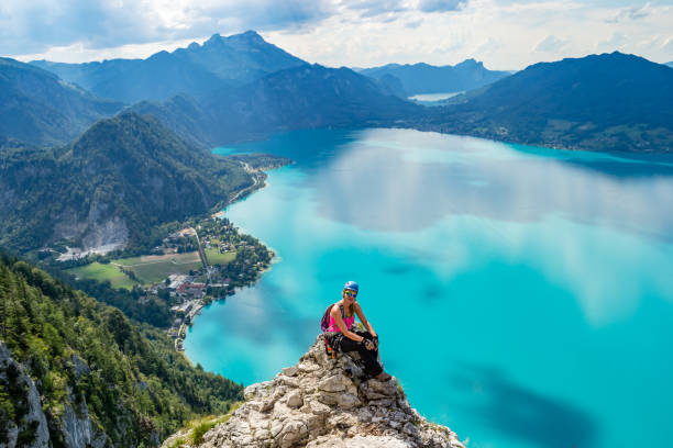erschöpftes, aber glückliches mädchen, das auf einer felswand über dem türkisfarbenen wasser des attersees eine pause einlegt, in oberem osten - austria european alps landscape lake stock-fotos und bilder