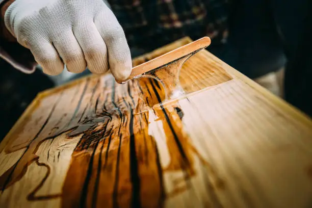 Photo of Male craftsman preparing varnishing of carpentry