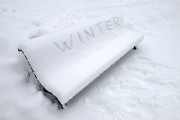 istock Park bench covered with snow and written Winter in English 1129920055