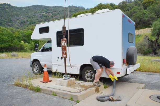 Man serving recreational vehicle in dumping station