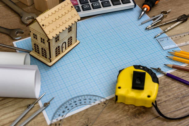 istock Wooden house model on millimeter paper with different tools 1129927550
