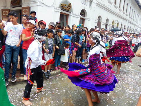 Cuenca, Azuay, Ecuador - February 6, 2016: Folk dancers beautiful girls dressed as cuencanas with baskets and flowers. Carnival in Ecuador is one of major national holiday and it is a public festivity. It is full of fun and entertainment. There are traditional parade on the main street Simon Bolivar at historical center of city. Folk dancers, kids and adults spray foam at each other in the streets to “play” Carnival.