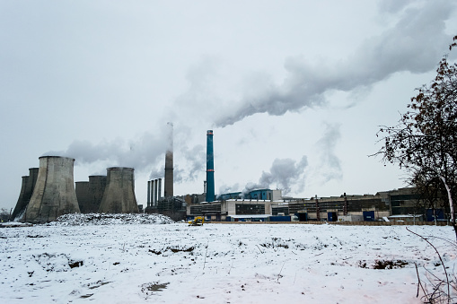 Severe air pollution from several coal burning power plants, with tall chimneys releasing fumes at sunset, in a cold Winter day - Bucharest, Romania