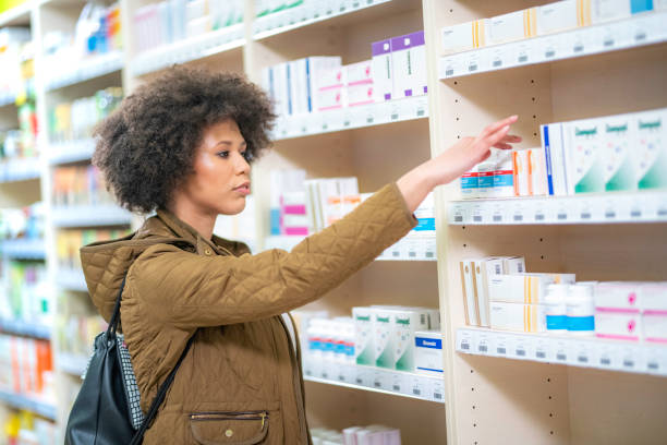 mujer joven elegir en droguería - pill bottle pharmacy medicine shelf fotografías e imágenes de stock