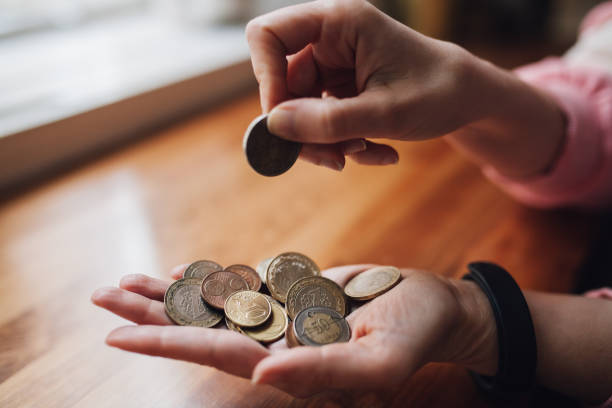 woman counting coins in her hand - women savings uk coin imagens e fotografias de stock