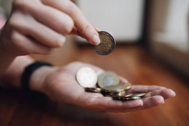 woman counting coins in her hand - women savings uk coin imagens e fotografias de stock