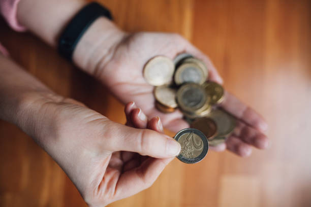 woman counting coins in her hand - women savings uk coin imagens e fotografias de stock