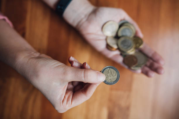 woman counting coins in her hand - women savings uk coin imagens e fotografias de stock