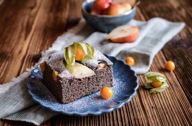 Poppy seed sponge cake with physalis and pear, sprinkled with powdered sugar