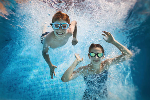 istock Brother and sister playing in swimming pool. 1129941883