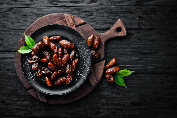 istock Dry date in a bowl on a black background. Dried fruit Top view. Free space for your text. 1129943856