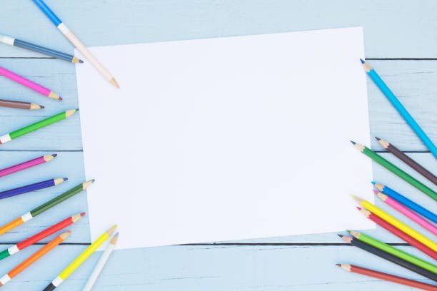 istock Color pencils with blank paper on wooden background. 1129949429