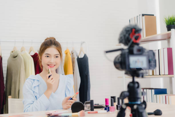 istock Beauty blogger present beauty cosmetics while sitting in front camera for recording video. Beautiful woman use powder while review make up tutorial broadcast live video to social network by internet. 1129964779