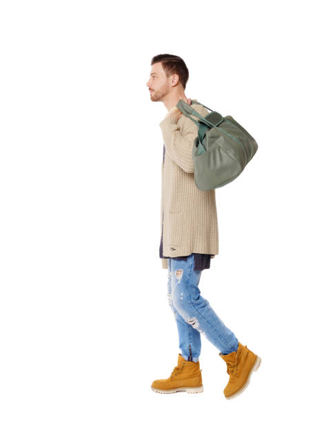 istock back view of walking  man  with green bag. 1129985507