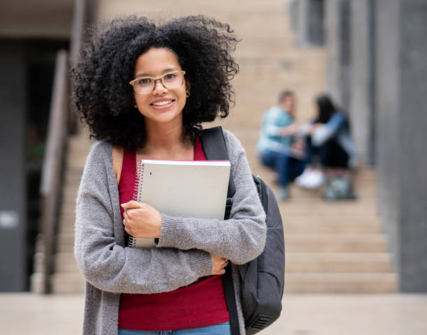 istock African american beautiful female college student embracing her notebook while facing camera smiling 1129999633