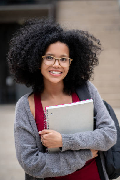 istock Cheerful young black college student holding her notebook and carrying backpack while smiling at camera 1129999648