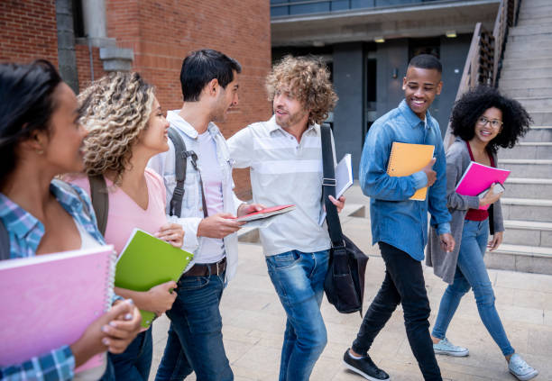 istock Multi ethnic group of friends walking around campus talking and smiling 1129999736