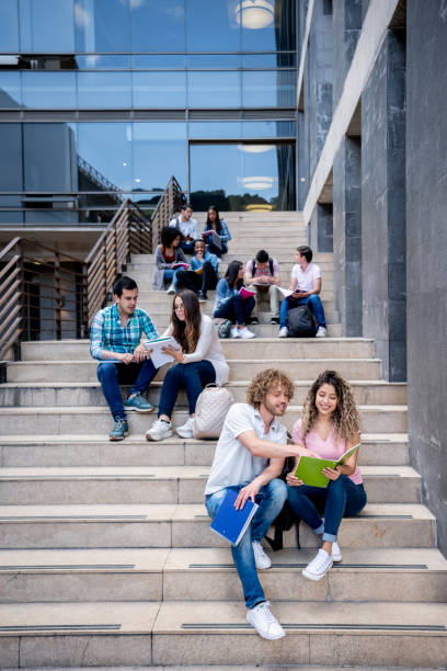 istock Group of college students sitting on stairs while studying all looking focused 1129999746
