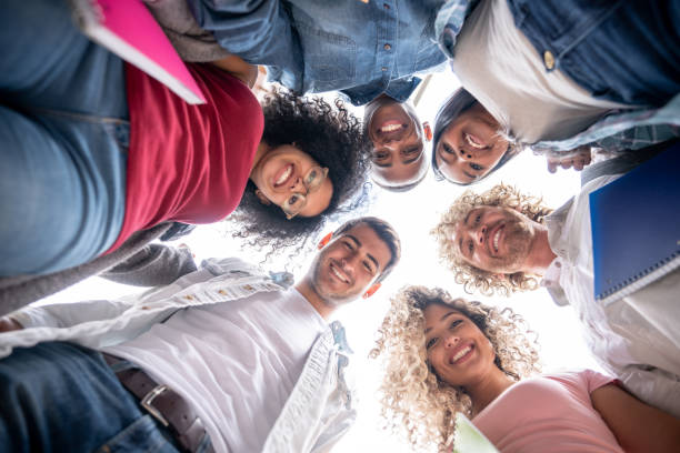 istock Group of diverse friends at college in a huddle facing camera smiling 1129999760