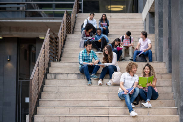 istock University students sitting on stairs studying looking at their notebooks 1130004610