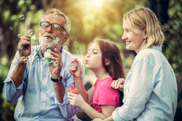 Happy family blows soap bubbles together while going vacation on weekend in the garden park in summer. Kid education and family activities concept. Happy family blows soap bubbles together while going vacation on weekend in the garden park in summer. Kid education and family activities concept. dv stock pictures, royalty-free photos & images