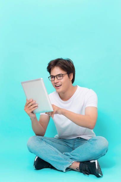 istock Young Asian man using a Pad PC isolated on blue background. 1130027712