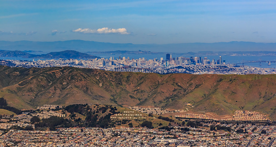 Aerial view of downtown San Francisco and Financial District sky scrapers flying over South San Francisco The Industrial City inscription on San Bruno mountain circa 2015