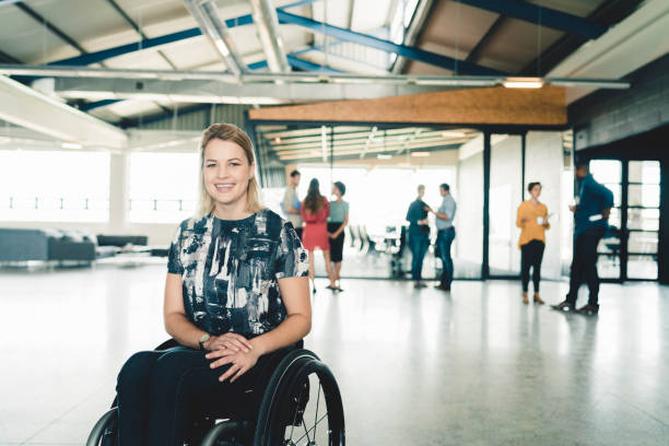 mujer de negocios feliz en silla de ruedas en oficina creativa - physical impairment smiling front view looking at camera fotografías e imágenes de stock