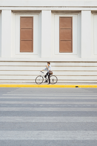 Going everywhere by his bike. Side view of young businessman looking forward while riding on his bicycle