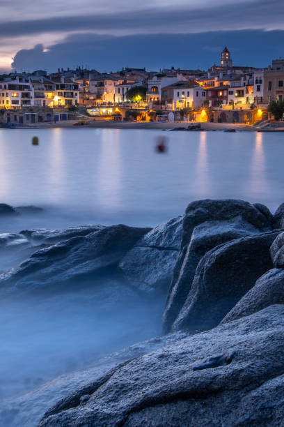 Tourist town next to the beach at sunset. Tourist coastal town of Calella de Palafrugell on the Costa Brava of Catalonia (Spain) during sunset with rocks in the foreground. paisaje urbano stock pictures, royalty-free photos & images