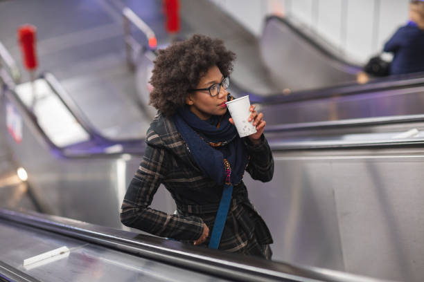 istock Beautiful young woman drinking coffee on escalator 1130045009