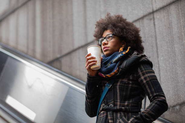 istock Beautiful young woman drinking coffee on escalator 1130045075