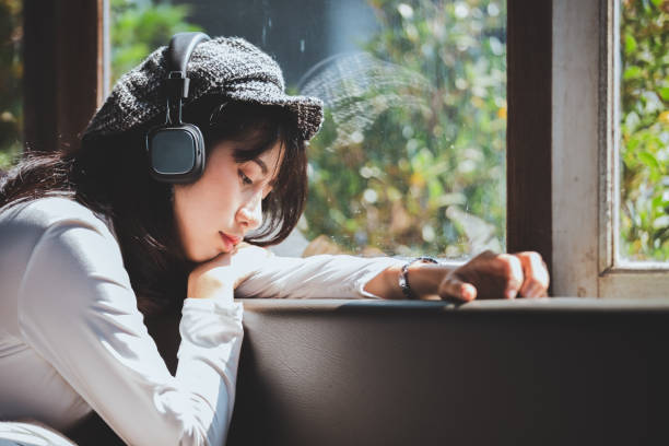 Emotion feeling young girl sad listening to music looking out the window stock photo