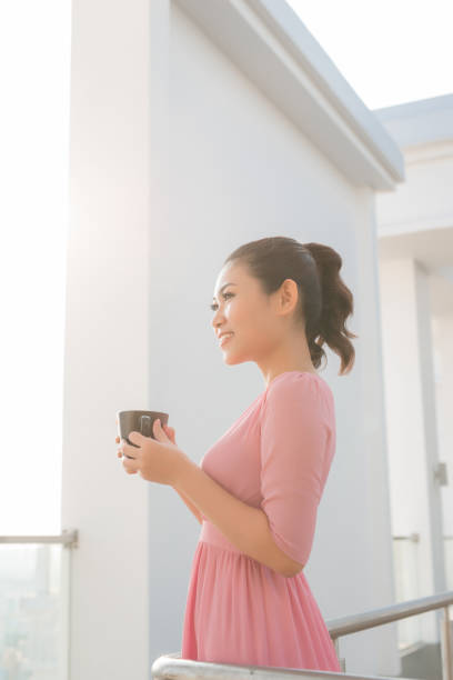 istock young woman holding coffee cup smiling 1130048185