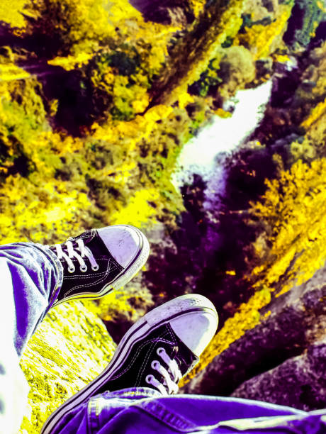 Feet clad in sneakers hang over the precipice Feet clad in sneakers hang over the precipice