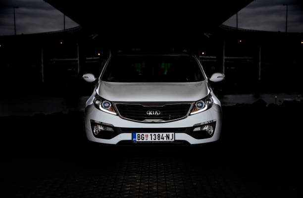 low key photo of suv kia sportage 2.0 crdi awd or 4x4, white color, under the bridge,  front of the  car,  the badge, and headlights. - europe bridge editorial eastern europe imagens e fotografias de stock