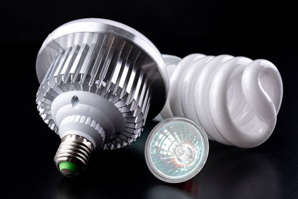 Different light bulbs and fluorescent lights on a wooden table. New types of lighting. Dark background.