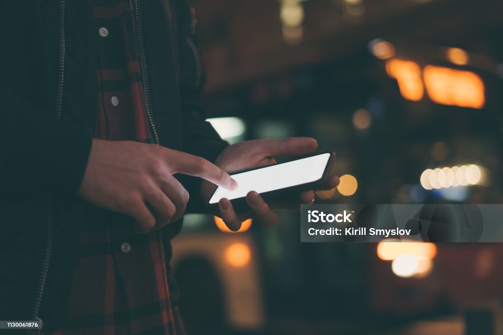 Male hands with smartphone Male hands with smartphone and night street on background Artificial Stock Photo