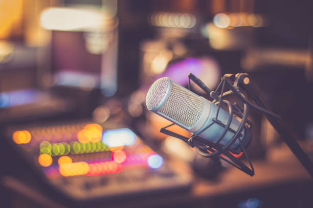 Microphone in a professional recording or radio studio, equipment in the blurry background Professional studio microphone, recording studio, equipment in the blurry background radio stock pictures, royalty-free photos & images