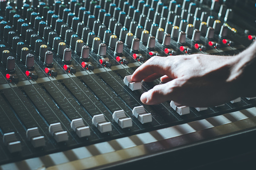 Professional music production in a sound recording studio, sound engineer is operating the mixing desk