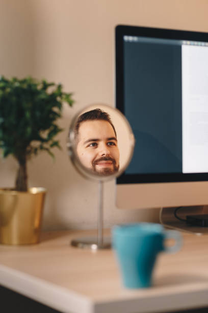 istock reflection of a young man working on a computer in his home office. 1130064134