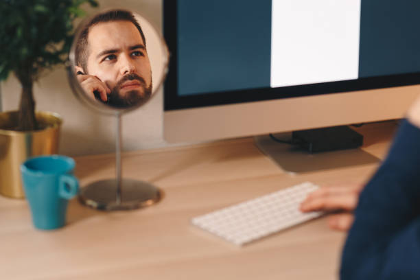 creative shot of a handsome young man working on a computer, reflection in a mirror