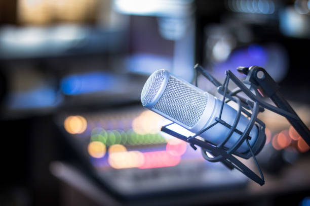 microphone in a professional recording or radio studio, equipment in the blurry background - microfone imagens e fotografias de stock