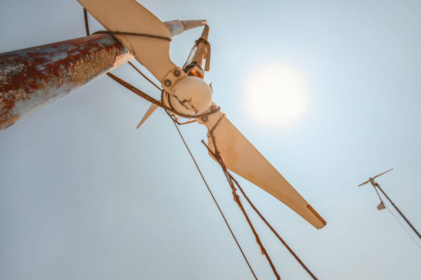 Looking up small broken wind turbine, strong midday sun shining in back
